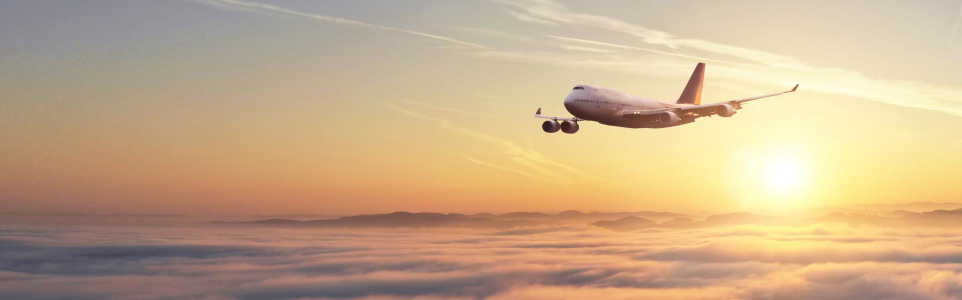 Airplane flying through a warm sunset sky